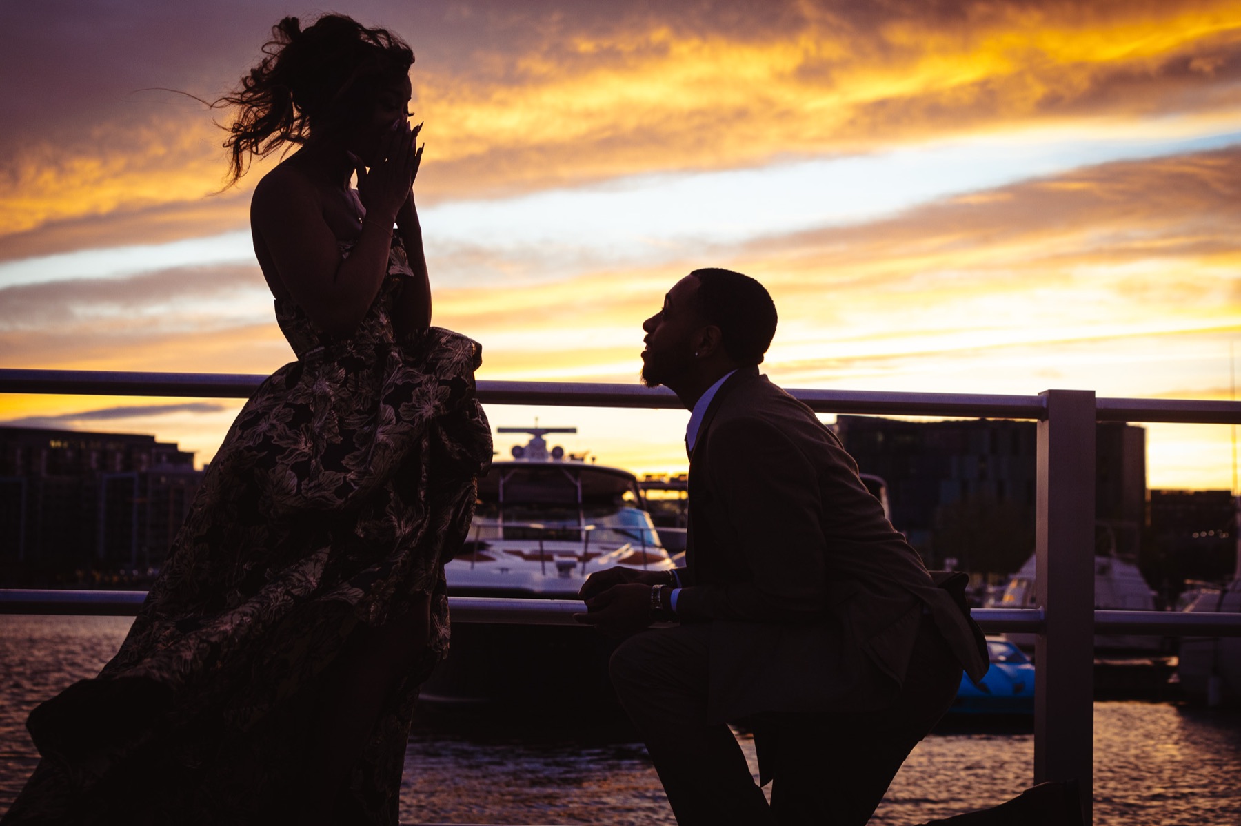Silhouette of Jelani on one knee proposing to Kimberly at sunset on the waterfront