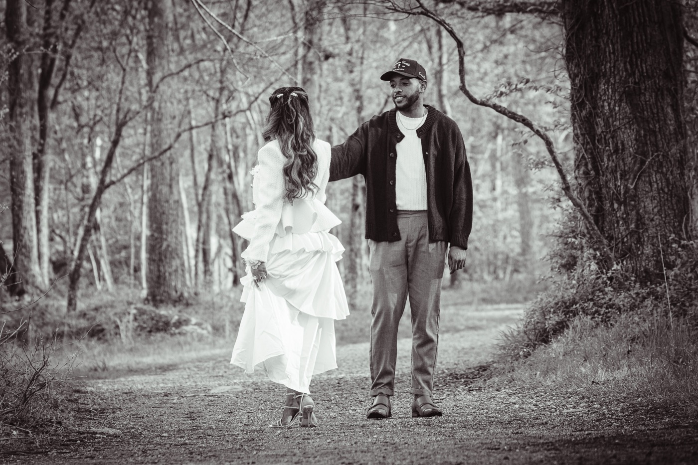 Black and white photo of Jelani reaching for Kimberly on a forest path