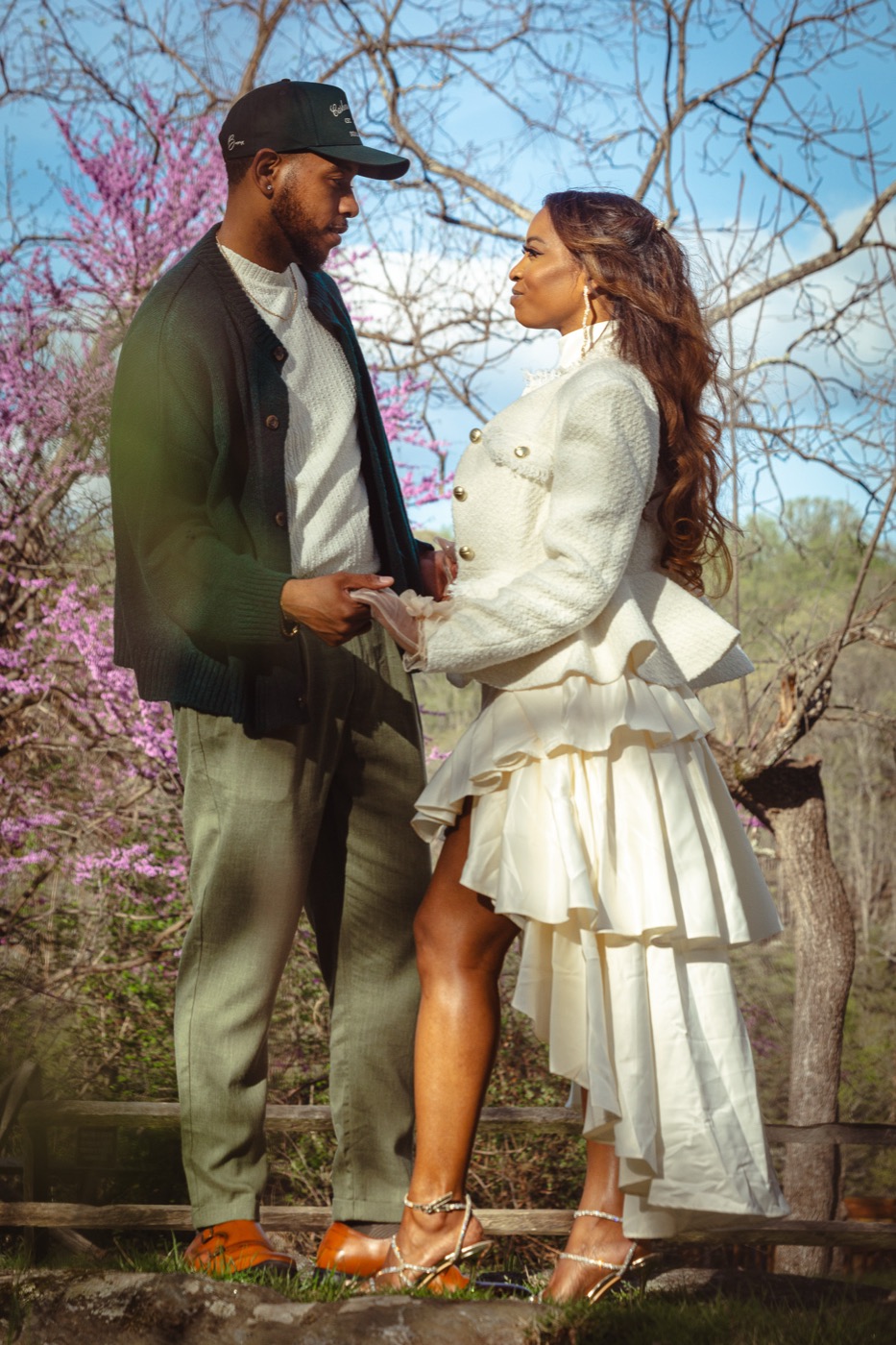 Kimberly and Jelani holding hands and gazing at each other beneath a blooming redbud tree