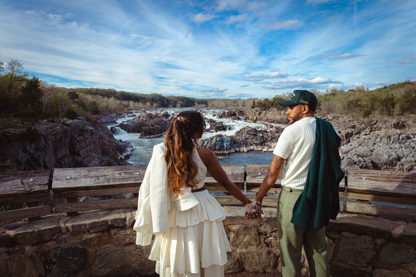 Kimberly and Jelani holding hands at a stone overlook above the rushing falls