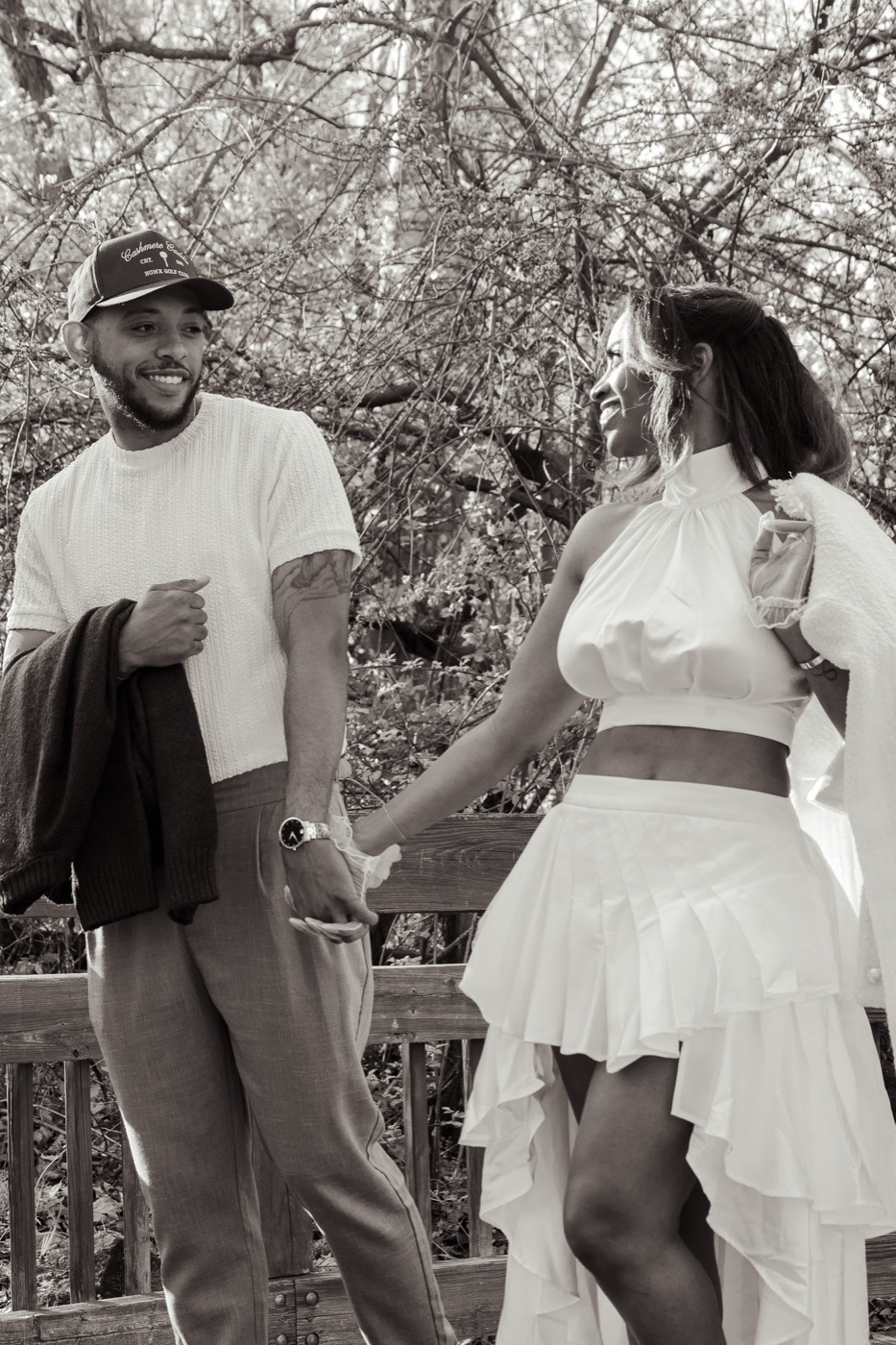 Black and white photo of Kimberly and Jelani smiling and holding hands on a bridge